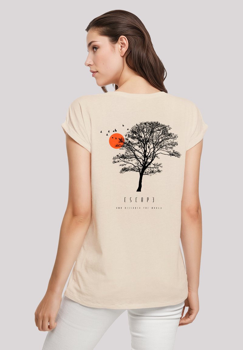 Beige short-sleeve t-shirt featuring a black tree silhouette, orange sun, and birds. Text below reads "ESCAPE AND DISCOVER THE WORLD."
