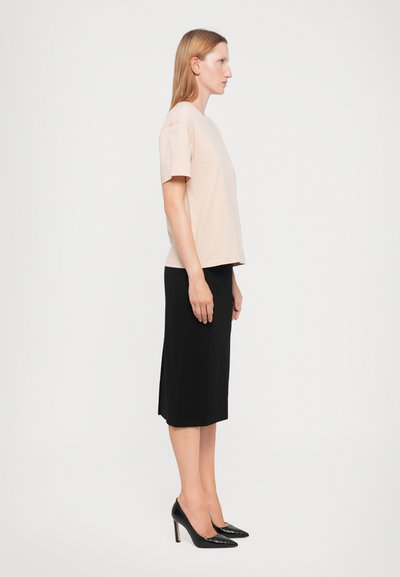 Light pink cotton t-shirt with short sleeves, paired with a knee-length black pencil skirt and black pointed-toe heels.