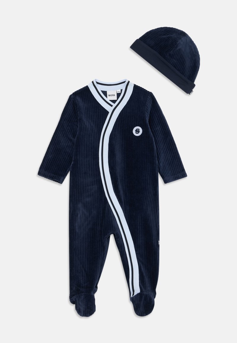 Tamsiai mėlyna štrichinė vienetė su ilgomis rankovėmis, balta akcento juostele, sukryžiuota priekyje ir mažąja apvalia etikete. Į komplektą įeina atitinkama tamsiai mėlyna kepuraitė.