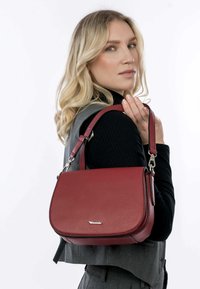 Red leather handbag with a structured design, smooth texture, and a single strap. Features silver hardware and a flap closure.