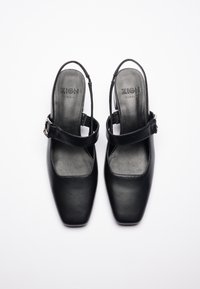 Sorte læder slingback sko med firkantet tå, justerbar rem og en glat tekstur. Branding synlig på indersålen.