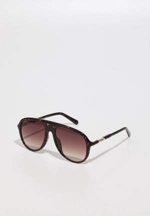 Sunglassit tortoise skelë me lentë gradiente, forma katrore, korniza të trasha dhe akcent metalik në krahë. Sipërfaqe e lëmuar në të gjithë.