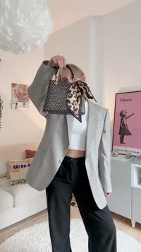 Black and beige patterned handbag with a fabric scarf handle. Features a geometric design, gold hardware, and compact shape.