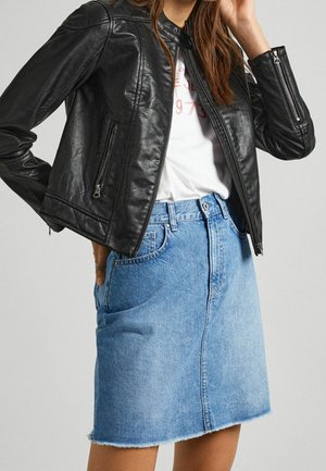 Kobieta w czarnej skórzanej kurtce na białym t-shircie z nadrukiem, zestawiona z jasnoniebieską spódnicą dżinsową z wysokim stanem i surowym wykończeniem.