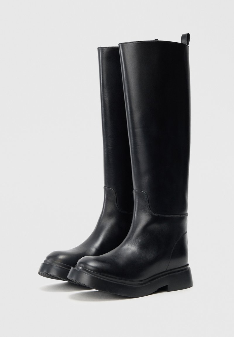 Stivali neri alti fino al ginocchio in pelle liscia. Presentano una punta arrotondata, suola robusta e un design semplice senza accessori visibili.