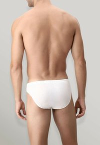 Slip in cotone bianco esposti su un modello maschile di spalle, con una morbida cintura elastica e una superficie liscia, minimamente texturizzata.