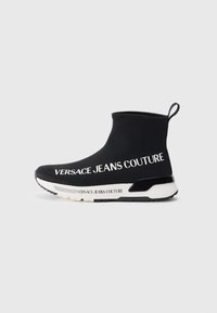 Melni potītes zābaki ar elegantu, stiepjamu dizainu, uz �ārējās puses ar baltu "Versace Jeans Couture" zīmolu un strukturētu zoli.