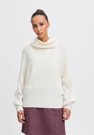 Cowlneck-Pullover aus weichem Creme-Strick mit weiten Ärmeln; kombiniert mit einem burgunderfarbenen Filzrock. Verfügt über Rippengummibündchen und eine gerade Silhouette.