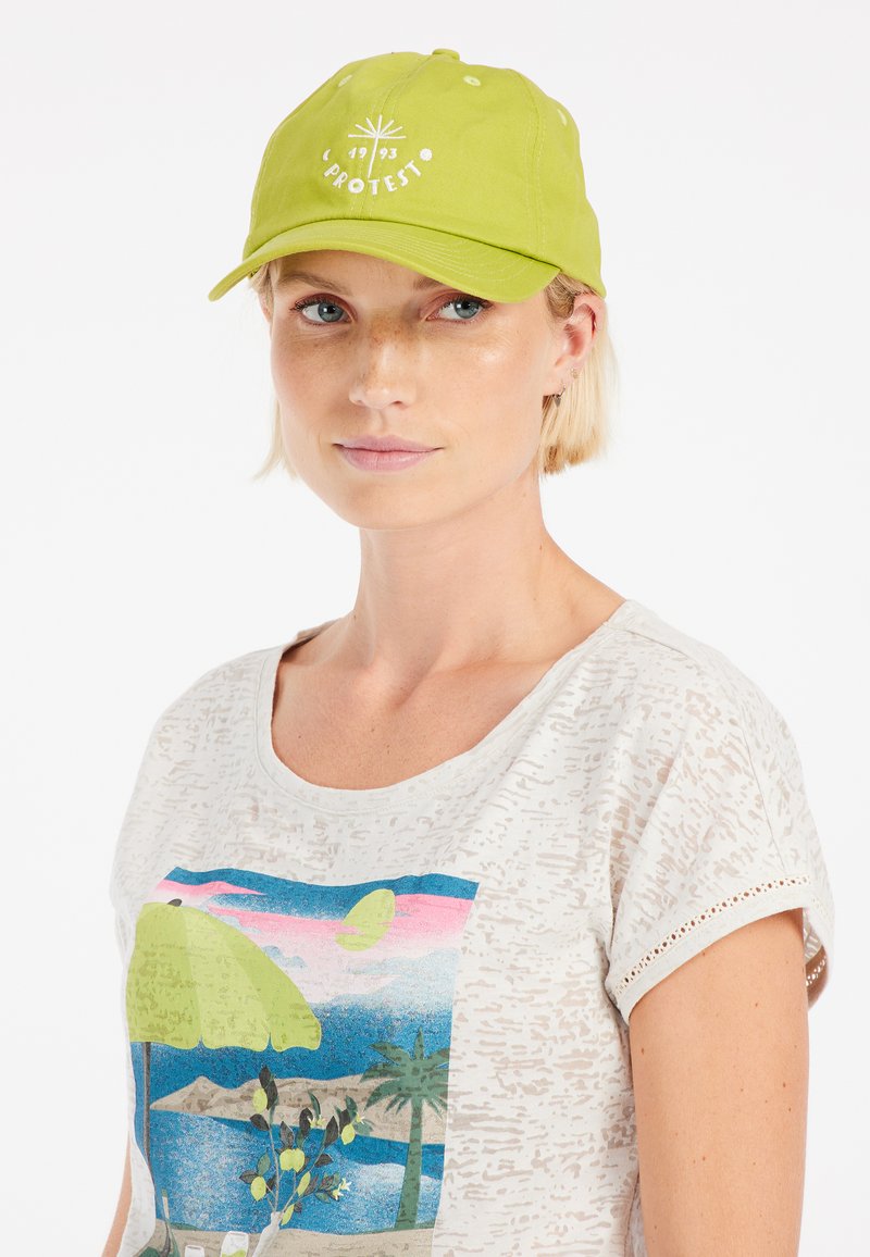 Groene honkbalpet met een gebogen rand en witte geborduurde tekst met een zonnestraalontwerp. De tekst bevat de merknaam "PROTEST."