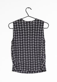 Černý bezrukávový top s bílou mřížkovou vzorem, vyrobený z hladké látky, s zakřiveným lemem a skladovým designem na bocích.