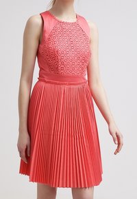 Korale sukienka z plisowaniem, z teksturowanym, wzorzystym bodicem oraz gładkim, jednolitym materiałem na ramionach i w talii, z dopasowanym krojem.