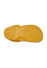 Geel rubberen zool met een gestructureerd grippatroon, met sculpturale lijnen en logo-details. Ontworpen voor comfort en stabiliteit.