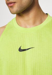 Primer plano de un hombre vistiendo una camiseta sin mangas atlética de color amarillo brillante con el logo negro de Nike en el pecho.