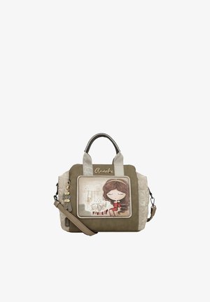 Piccola borsa a mano verde oliva e beige con illustrazione di una ragazza dei cartoni animati, ciondoli decorativi e il nome del marchio "Anekke" sulla parte anteriore.