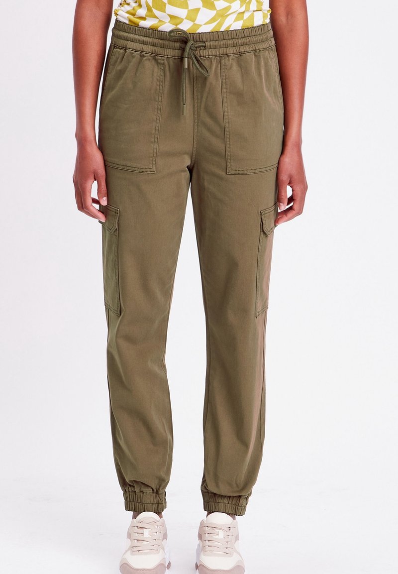 Pantalon de jogging vert olive avec une taille élastique, un cordon de serrage et des poches latérales. Ourlets effilés aux chevilles, fabriqué en tissu doux.