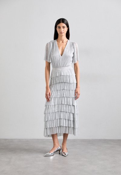 Silver tiered midi dress with short puff sleeves and a deep V-neck. Features a textured fabric. Paired with pointed metallic heels.