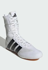 Weißer Sportschuh mit Obermaterial aus Mesh, schwarzem Drei-Streifen-Design und flacher Gummisohle. Verfügt über einen hoch geschnittenen Schaft und Schnürverschluss.