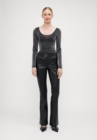 Svarte tettsittende skinnbukser med lett skjær, sammen med en metallisk glitrende langermet topp. Begge plaggene har en elegant, glatt finish.