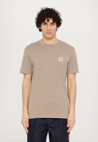 Kratká rukávová trička s kulatým výst�řihem v taupe bavlně, s malým čtvercovým logem v levém horním rohu. Jednoduchý a minimalistický design.