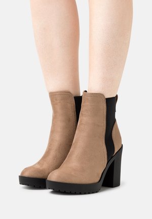 Bruna mockaankelboots med hög svart klossklack och elastiska sidor. Slät textur med en rundad tådesign.