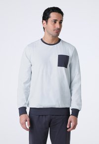 Felpa a maniche lunghe azzurro chiaro con collo a girocollo blu navy, polsini e vita elasticizzati, dotata di una tasca sul petto blu navy. Texture del tessuto morbida.