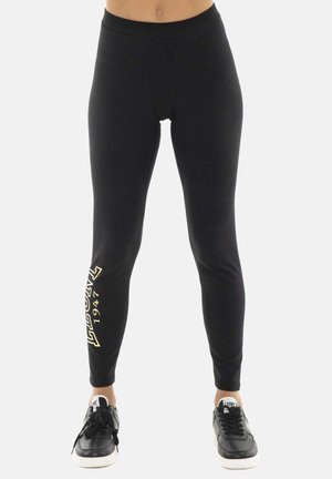 Leggings neri aderenti con la scritta "LEONE 1947" sulla gamba sinistra, indossati con scarpe da ginnastica nere e bianche.