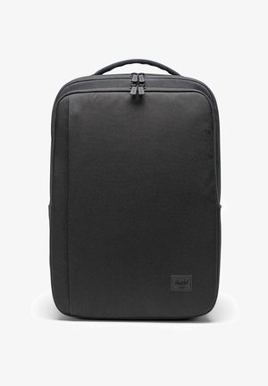 Sac à dos noir en tissu texturé, avec une fermeture éclair, une poignée rembourrée et un petit logo de marque dans le coin inférieur droit.