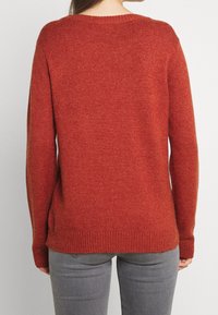 Rustinvärgad stickad tröja med ribbad nederkant och muddar, rund halsringning och lös passform, tillverkad av ett mjukt, strukturerat tyg.