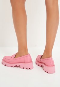 Roze nepleer instapschoenen met een dikke, gegroefde buitenzool en stiksels op de bovenkant. Rugloze ontwerp met een ronde neus.