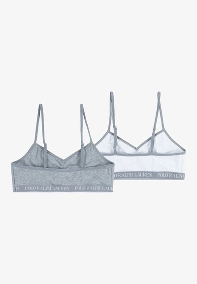 Dve bralette v svetlo sivi in beli barvi, ki imata mehko tkanino, nastavljive naramnice in logotipni pas ob dnu.