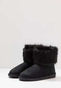 Botas negras de tobillo de suave ante con un puño de pelo sintético en la parte superior. Punta redondeada y suela texturizada para mayor agarre.