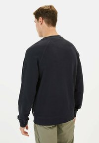 Donkerblauwe sweatshirt met een ronde hals, raglanmouwen, geribbelde manchetten en zoom. Beschikt over een discreet zijrits en een zachte textuur.