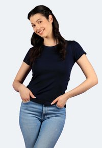 Maglietta a maniche corte fitted blu navy in morbido cotone, abbinata a jeans in denim blu chiaro, caratterizzati da una superficie liscia e una silhouette classica.