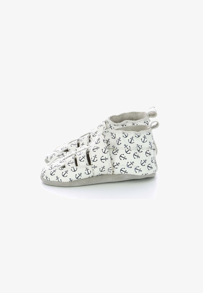 Zapatos blancos para toddlers con un estampado de anclas azul marino, que cuentan con un upper de textura suave, doble correas de Velcro y una suela de ante gris.