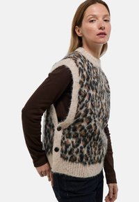 Gilet en tricot avec un motif léopard en tan, noir et marron, avec une texture douce, un design sans manches et des accents de boutons sur le côté.