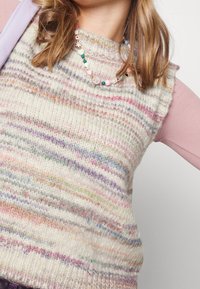 Gilet lavorato a maglia in colori pastello con righe orizzontali in tonalità crema, rosa, blu e verde. Presenta un design senza maniche e un tessuto con texture.