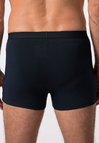 Černé bavlněné boxerky s těsným střihem, které mají měkký pas s embosovaným nápisem "JP1880." Hladká textura a bez viditelných vzorů.