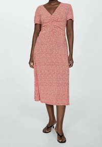 Vestido midi rojo con estampado floral, de manga corta, con escote en V y detalle fruncido en la cintura. Tejido suave con un ligero brillo y falda fluida.