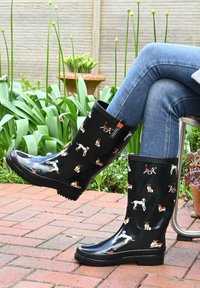 Black waterproof rubber rain boots featuring a dog pattern in various colors, with a textured sole and a cushioned lining for comfort.