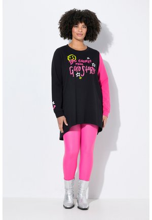 Black long-sleeve tunic with pink sleeve and graphic text, paired with glossy pink leggings and silver ankle boots.