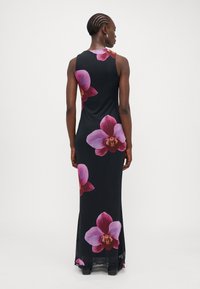 Robe maxi en tissu noir ornée de grandes impressions d'orchidées roses et violettes. Design sans manches avec une coupe près du corps et un ourlet fluide.