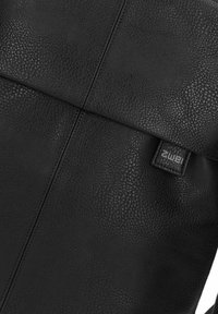 Bolso de cuero negro con una superficie texturizada, forma rectangular y un parche de marca. Presenta líneas limpias y un diseño minimalista.