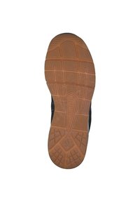 Suela de zapatilla negra con una superficie de goma texturada, que presenta un patrón de dibujo de goma marrón para agarre y tracción.