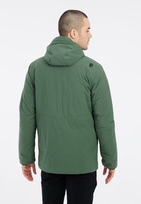 Chaqueta verde con capucha, aislante y de textura suave; presenta un logo en el hombro y un diseño sencillo. La vista trasera muestra los detalles de costura.