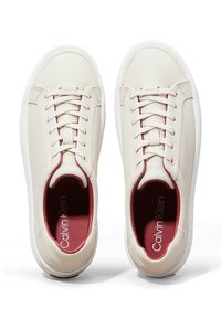 Hvide lædersneakers med runde gummisåler, der har beige snørebånd og en bordeauxfarvet detalje omkring anklen. Viser Calvin Klein-logoet indeni.