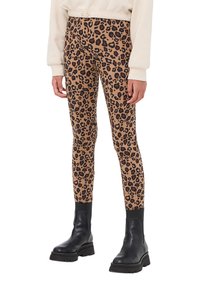Leggings in stampa leopardata su base marrone chiaro con macchie nere, caratterizzati da un design aderente e abbinati a stivaletti neri.