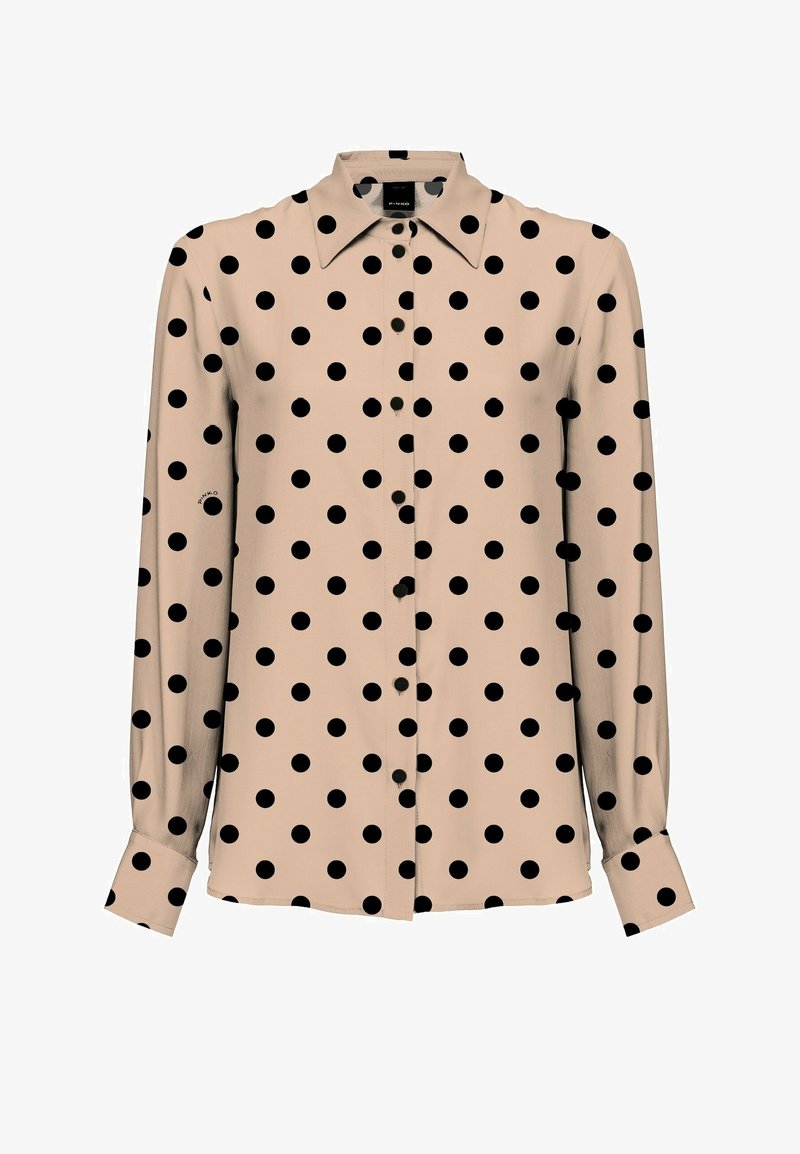 Chemise beige à manches longues boutonnée avec des pois noirs et un col pointu.