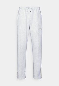 Světle šedé tepláky vyrobené z měkké směsi bavlny, s elastickým pasem na šňůrku, bočními kapsami a zipy na kotnících. Vytlačené logo jako detail.