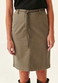 Jupe verte olive fabriquée en tissu léger, avec un design ajusté, une ceinture à cordon de serrage et un ourlet au niveau du genou.