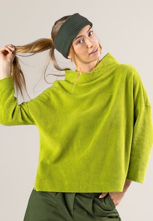 Grüner Fleece-Oberteil mit lockerer Passform, hohem Kragen und abfallenden Schultern. Strukturierter Stoff und ein geripptes, dunkelgrünes Stirnband vervollständigen den Look.